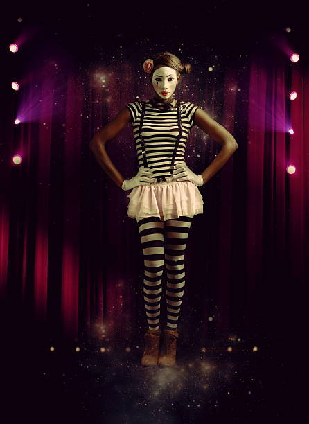 Portrait of a young African lady dressed up as a mime posing on a theatre stage.