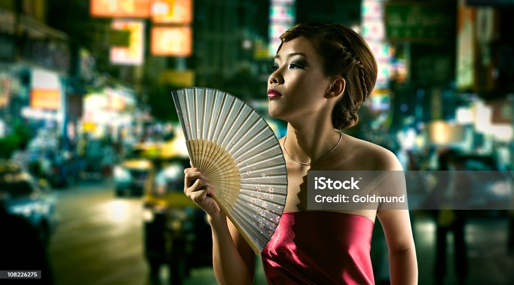 Giovane donna cinese Fanning sola notte al centro città - Foto stock royalty-free di Città