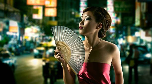 Young Chinese Woman Fanning Herself Downtown at Night stock photo
