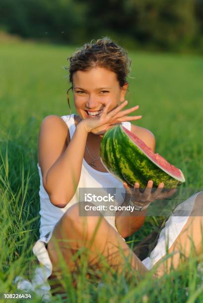 Ritratto Di Una Giovane Donna Mangiare Anguria In Erba Verde - Fotografie stock e altre immagini di Anguria