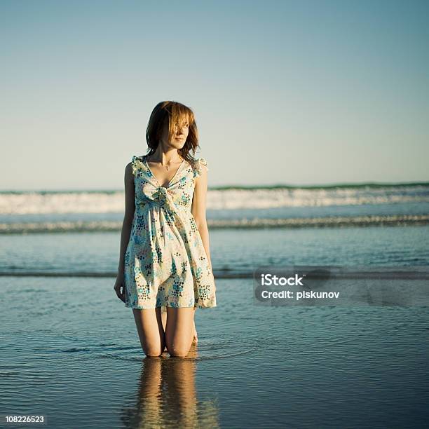 Young Woman Kneeling On Beach Stock Photo - Download Image Now - Adult, Adults Only, Brown Hair