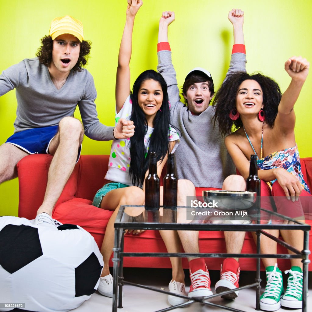 Grupo de jovens de estar e comemorando no sofá - Foto de stock de Fã royalty-free