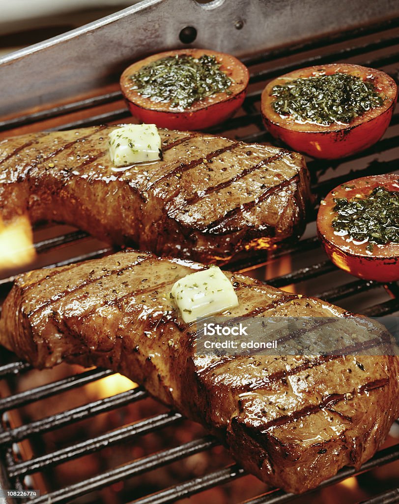 Steaks and Tomatoes on Barbeque Grill Meat NY striploin and tomato on grill Barbecue Grill Stock Photo