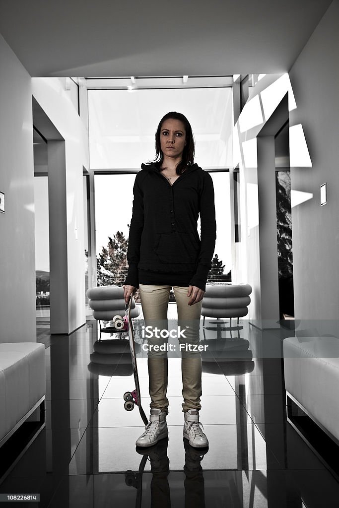 Młoda kobieta trzyma Deskorolka w nowoczesnym domu - Zbiór zdjęć royalty-free (Budowla mieszkaniowa)