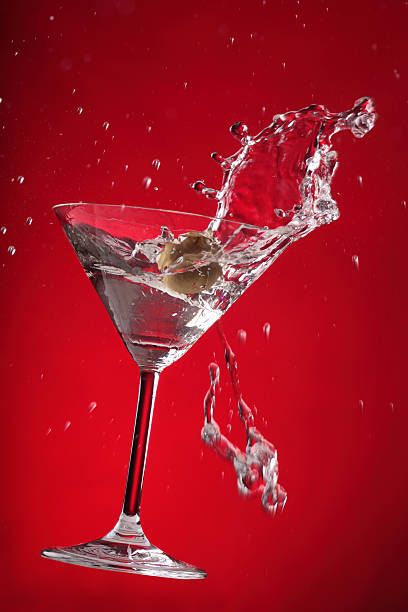 martini éclaboussures sur fond rouge - cocktail alcohol red martini glass photos et images de collection