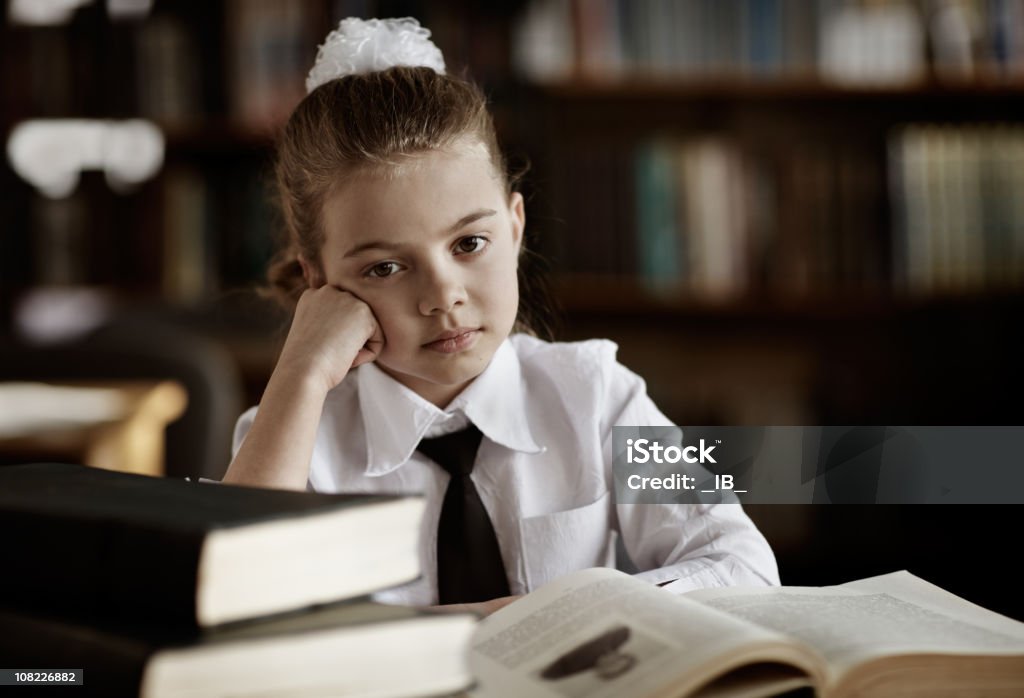 Marre petite fille en Uniforme scolaire dans la bibliothèque - Photo de 8-9 ans libre de droits