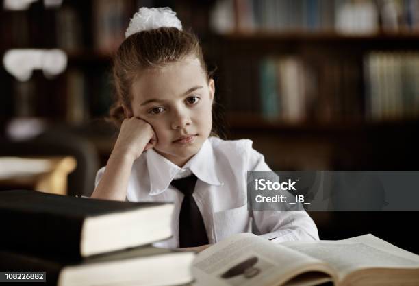 Photo libre de droit de Marre Petite Fille En Uniforme Scolaire Dans La Bibliothèque banque d'images et plus d'images libres de droit de 8-9 ans