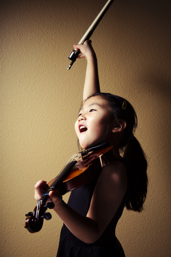 Horizontal composition. preteen practicing violin in her bedroom.