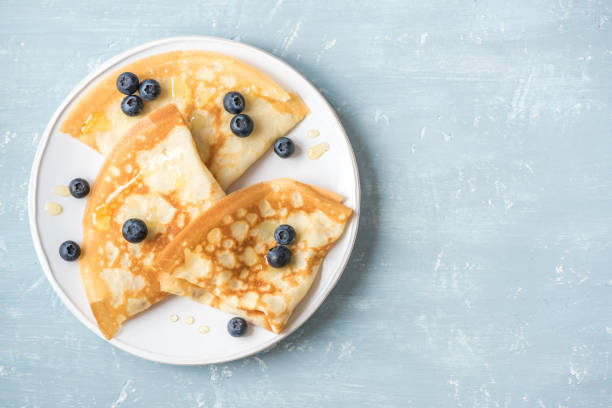 Crepes with blueberries and honey Crepes with blueberries and honey. Homemade pancakes, crepes on blue table, copy space. blini photos stock pictures, royalty-free photos & images