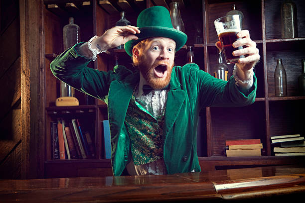 Irish Character / Leprechaun Celebrating with Pint of Beer A "Leprechaun" looking man with red hair and beard, in a full green suit complete with vest, bow tie, and top hat, perfect for St. Patrick's Day.  He stands at an old fashioned Irish bar with a glass of beer in his hand dancing and tipping his hat.  Horizontal with copy space. tail coat photos stock pictures, royalty-free photos & images