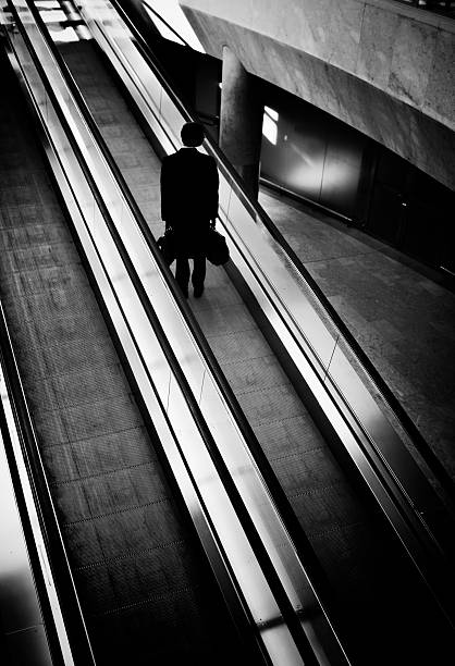 sagoma di uomo d'affari in viaggio su scala mobile, bianco e nero - moving walkway escalator airport walking foto e immagini stock