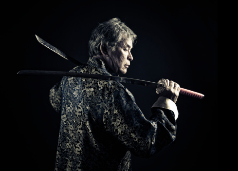 asian guy wearing a chinese suit and holding japanese katanas
