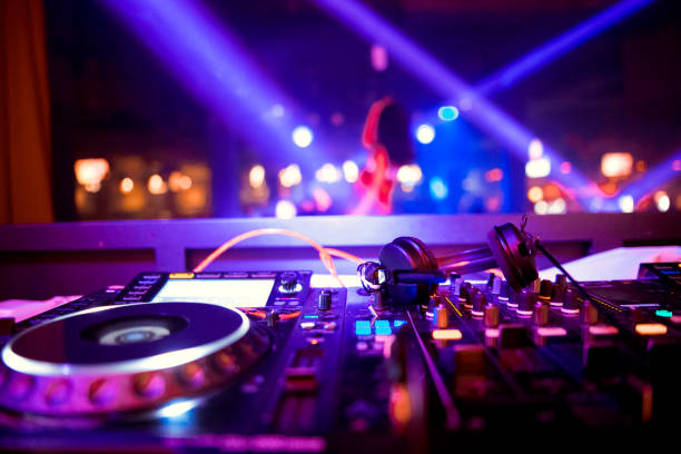 istock In selective focus of Pro dj controller.The DJ console deejay mixing desk at music party in nightclub with colored disco lights. Close up view 1082271646
