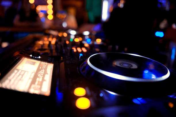 istock In selective focus of Pro dj controller.The DJ console deejay mixing desk at music party in nightclub with colored disco lights. Close up view 1082274026