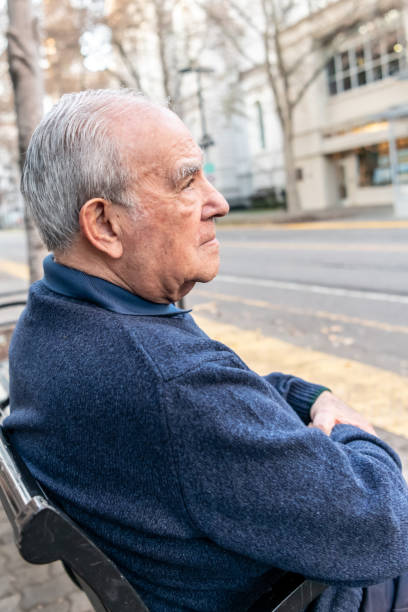 istock Old man sitting in a city bench 1082279012