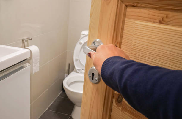 close up woman hand with dark blue sweater open the toilet door handle stock photo