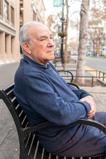 istock Old man sitting in a city bench 1082281212