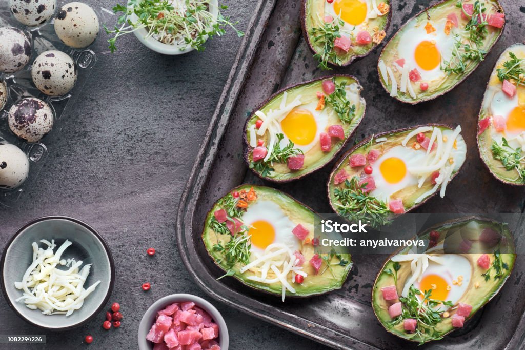 Plato de dieta ceto: aguacates barcos con cubos de jamón, huevos de codorniz, brotes de berro y queso - Foto de stock de Aguacate libre de derechos