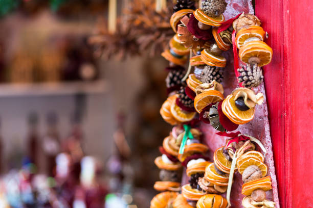 Close up color image depicting unique, handmade Christmas decorations made from slices of dried citrus fruit, walnuts and pine cones in a row and for sale on a market stall at an Christmas market. Room for copy space.