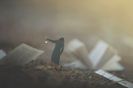 surreal moment of a woman with lantern walking confused in the fog between pages and books