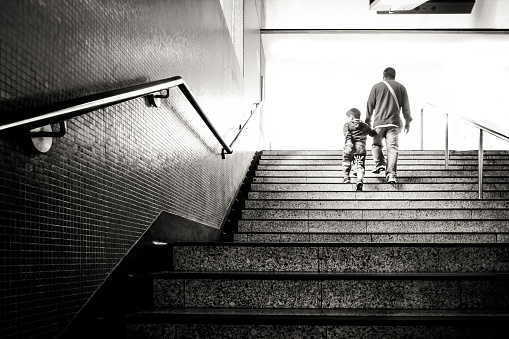 A man holding his grandchild walking up a staircase in Hong Kong Metro Station