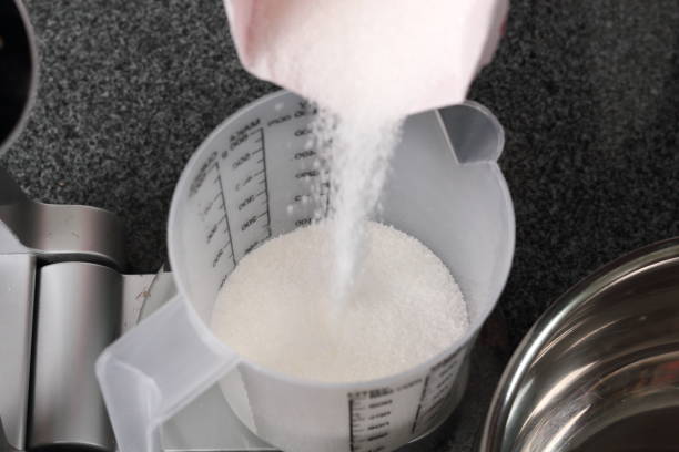 istock Pouring Sugar into Measuring Cup on Kitchen Scale. Making Golden Syrup Series. 1082312602