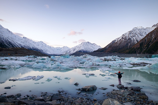 A traveler viewing the amazing icebergs and snow mountains during dusk in New Zealand. This place is famous among tourists, backpackers, hikers and locals. The scenery is beautiful.