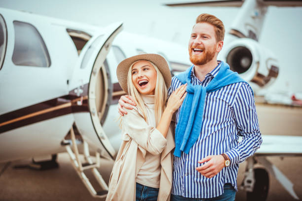 istock Young rich couple walking away from a private airplane parked on a runway after getting together. 1082319582