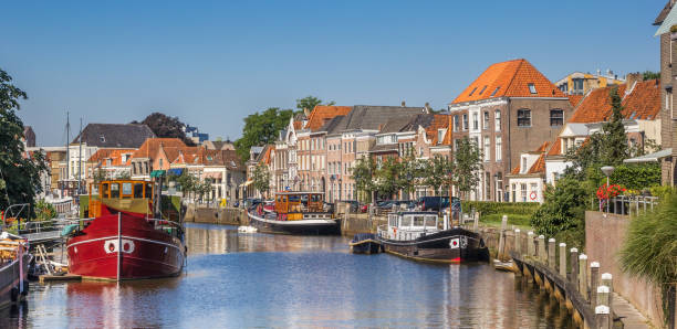 panorama of a canal with old ships and historical houses in zwolle, the netherlands - hanse imagens e fotografias de stock