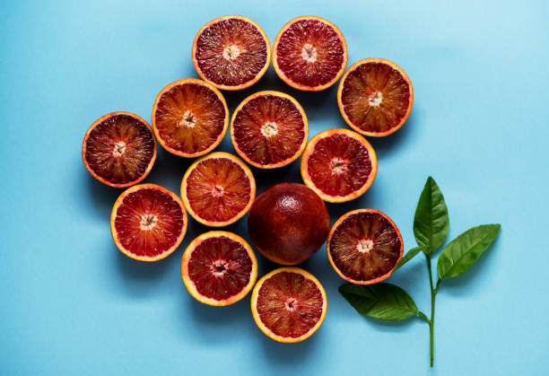 istock Citrus background pattern with red oranges and green leaves on a blue background. Flat lay 1082333674