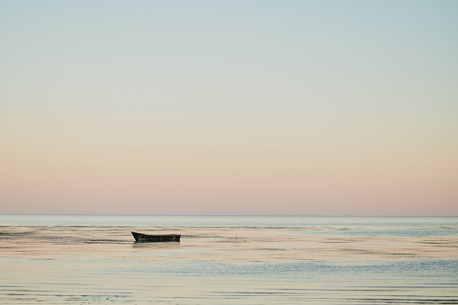 Small fishing boat in bay at dusk sunset