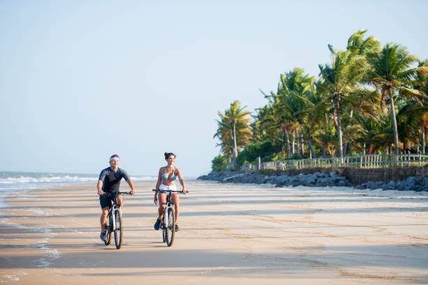 istock Couple riding bikes on beach in Brazil 1082344320