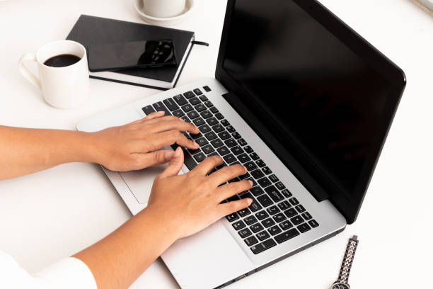 istock Business woman type on laptop computer on white office desk 1082349666