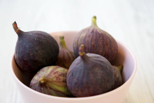 istock Fresh figs in a pink bowl on a white wooden background, side view. Closeup. Selective focus. 1082350110