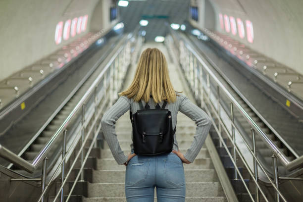 mujer en escaleras mecánicas en la estación de metro - escalera mecánica fotografías e imágenes de stock