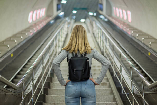 woman on escalator in subway station - escalator imagens e fotografias de stock