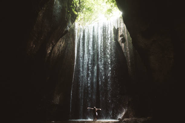 istock Woman staying under hidden waterfall in cave on Bali 1082357308