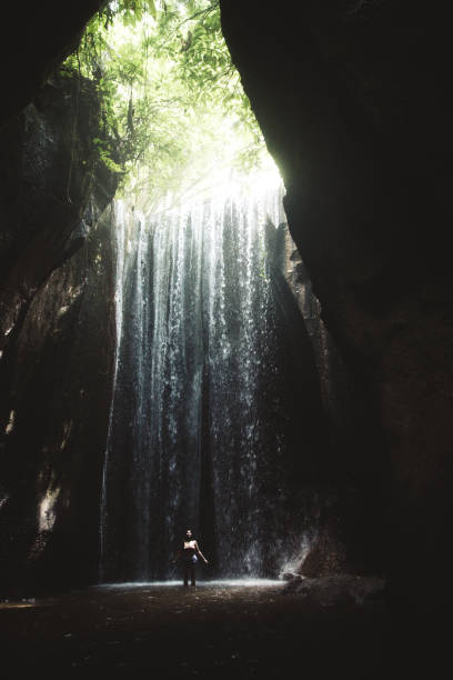 istock Woman staying under hidden waterfall in cave on Bali 1082357526