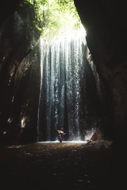 istock Woman staying under hidden waterfall in cave on Bali 1082357676