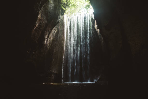 istock Woman staying under hidden waterfall in cave on Bali 1082359166