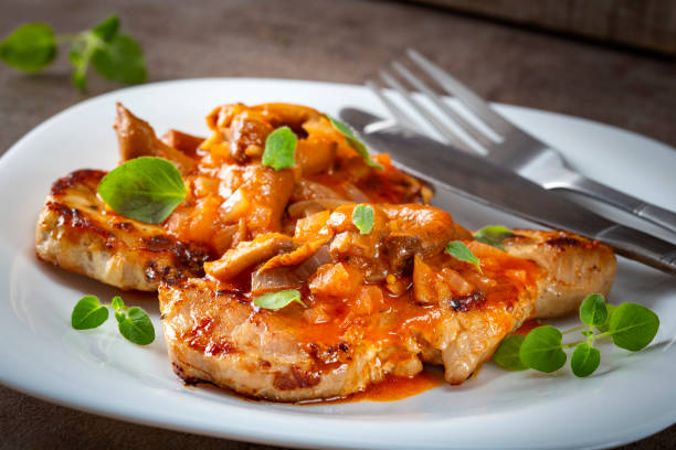 istock Fried pork chops with vegetables sauce and herbs on a white plate 1082359224