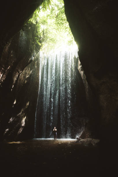 istock Woman staying under hidden waterfall in cave on Bali 1082359254