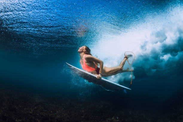 istock Surfer woman with surfboard dive underwater 1082362808