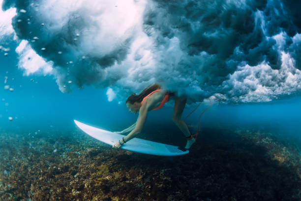 istock Attractive surfer woman dive under crashing barrel wave. 1082362816