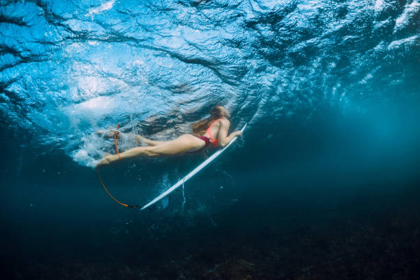 istock Surfer girl in bikini with surfboard dive underwater and wave 1082363914