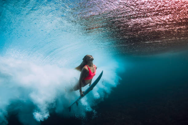 istock Sporty surfer woman dive underwater with under barrel wave. 1082363922
