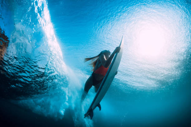 istock Attractive surfer woman dive underwater with under barrel wave. 1082363978