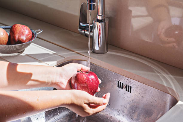 istock Female hands washing red apple in sink 1082369418
