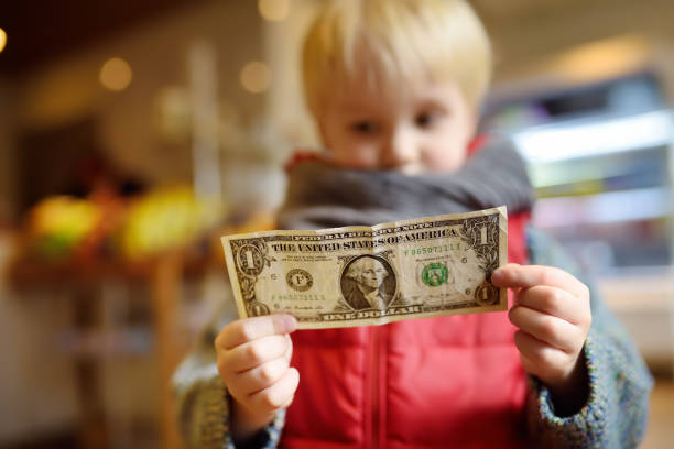 niño tiene una nota de la moneda de un dólar. - 7653 fotografías e imágenes de stock