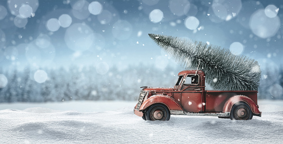 Old red toy truck with christmas tree loaded on the back